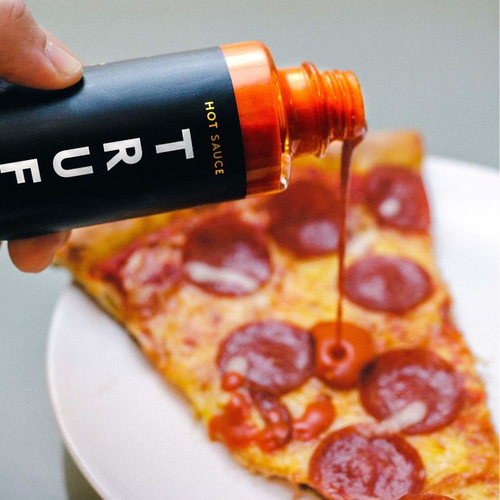 Truffle hot sauce being drizzled over pizza