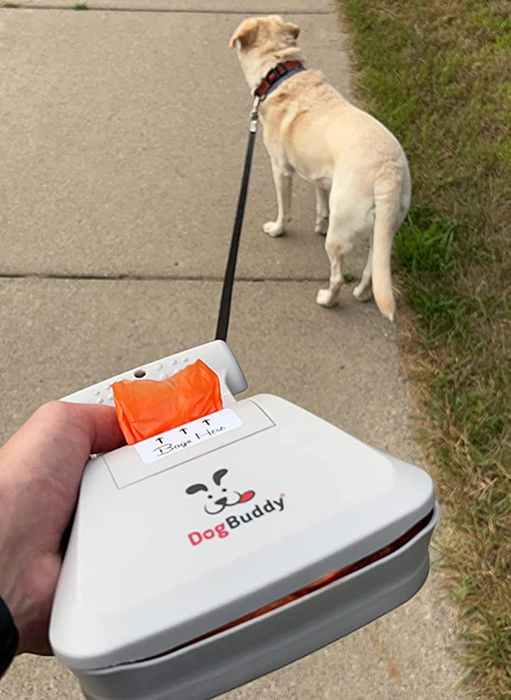 A reviewer holding the scooper mechanism, with the built-in bags attached to their dog’s leash