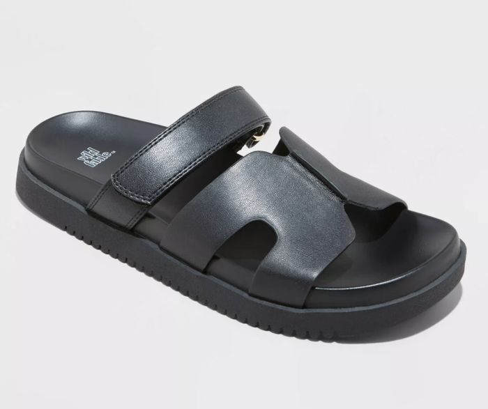 A black slide sandal with two wide straps, one secured with Velcro, and a textured sole for added comfort and support