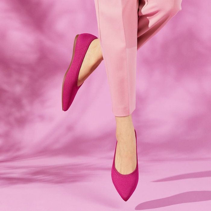 A model poses in vibrant hot pink ballet flats.