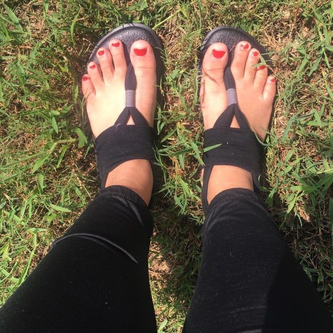 reviewer sporting flat thong sandals with black soles and black straps