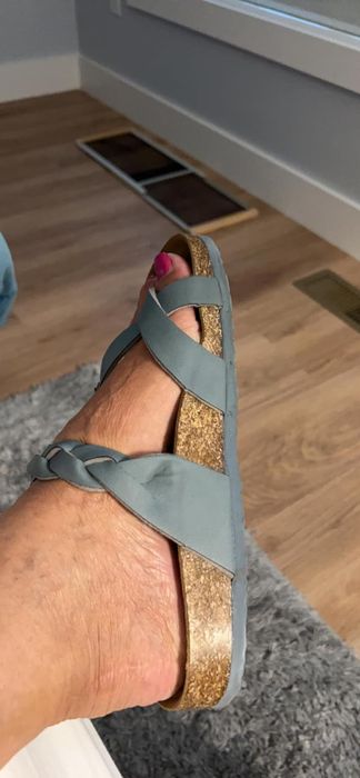 A reviewer’s foot shown wearing sandals with crisscross straps over the top and a cork sole.