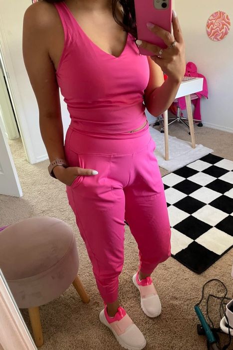 A reviewer taking a mirror selfie in a sleeveless hot pink top and matching joggers.