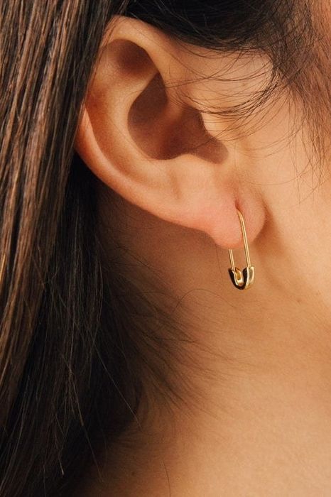 A model showcasing the gold safety pin earrings