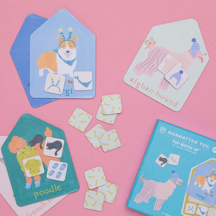 Four cards from a children's matching game showing different dog breeds against a pink background