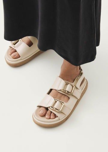 A close-up of a model wearing ivory sandals.