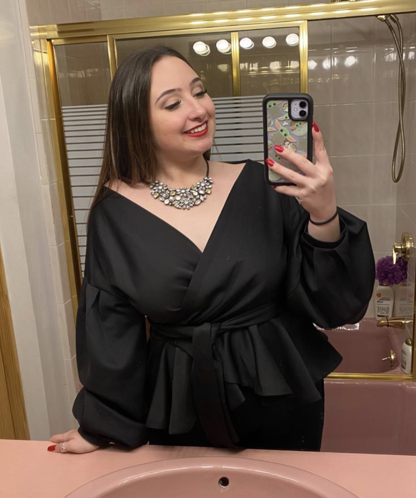 Reviewer wearing the black off-shoulder top paired with a statement necklace