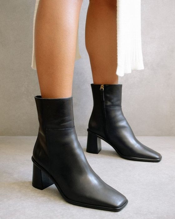 A side view of the boots on a model, highlighting the heel and zipper detail.