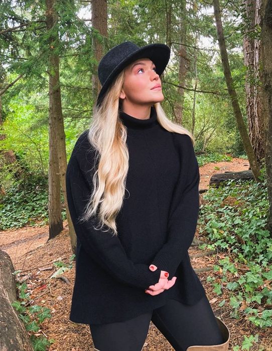 A reviewer wearing the black version of the sweater.