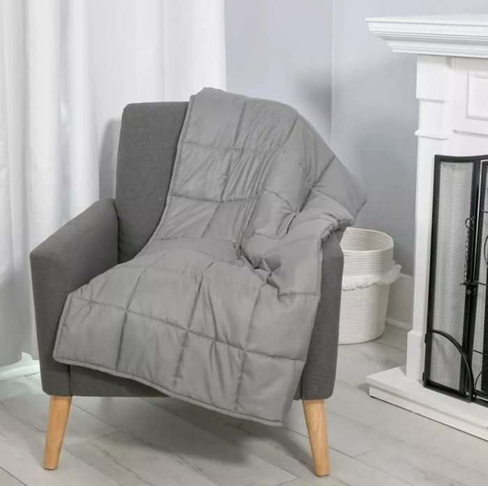 A grey weighted blanket resting on an accent chair