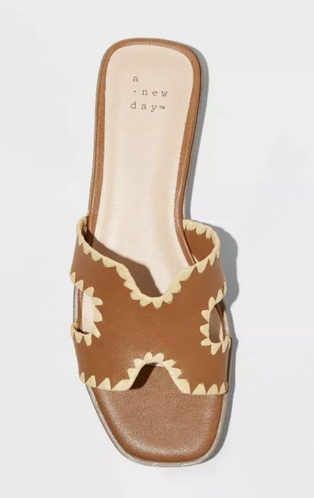 Brown slip-on sandal featuring scalloped edges and floral cut-out designs on the straps