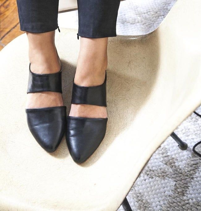 Model wearing the pointed-toe open-back flat with a cutout over the top of the foot.