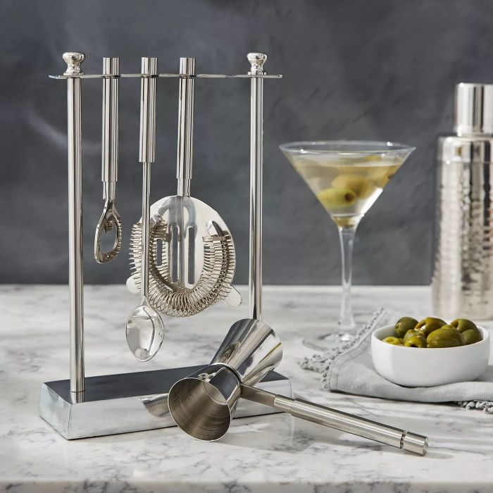 The sleek silver cocktail set, complete with a matching stand, displayed on a polished marble countertop.