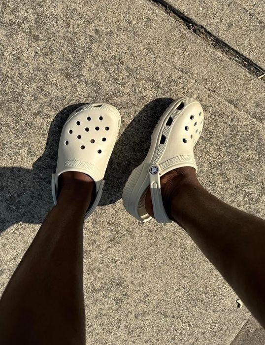 A reviewer showcasing white Crocs sandals.