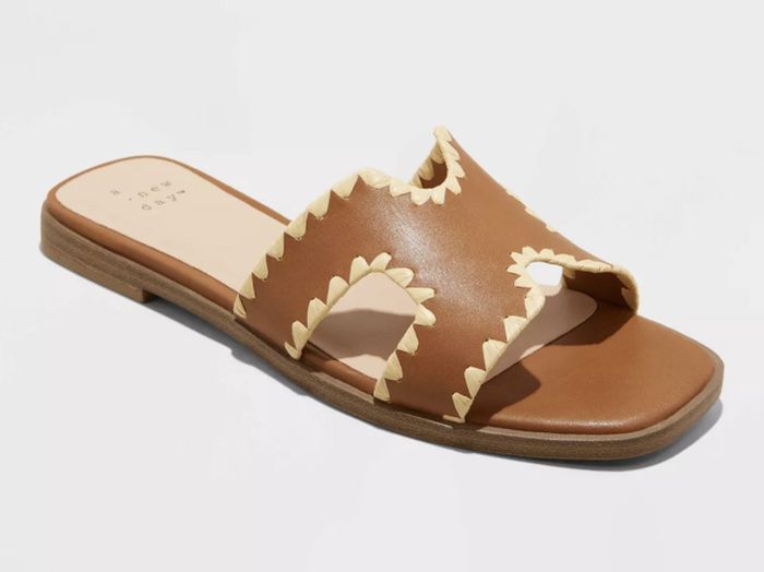 A single brown leather sandal with scalloped edges, showcased against a white background