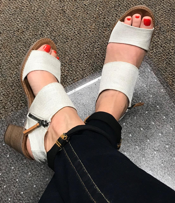 An overhead view of a reviewer wearing white sandals.