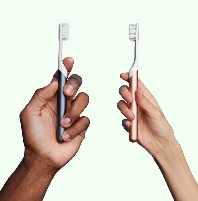 Two models, each holding a Quip electric toothbrush