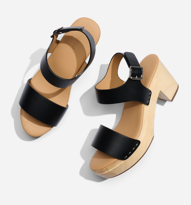 The clogs featuring black leather straps and a chunky wooden sole