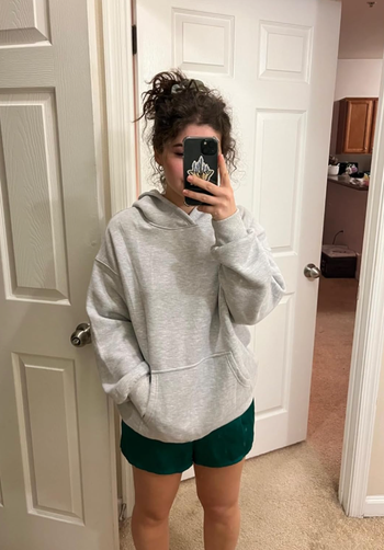 A reviewer wears a marled gray hoodie, exuding a relaxed, casual feel.