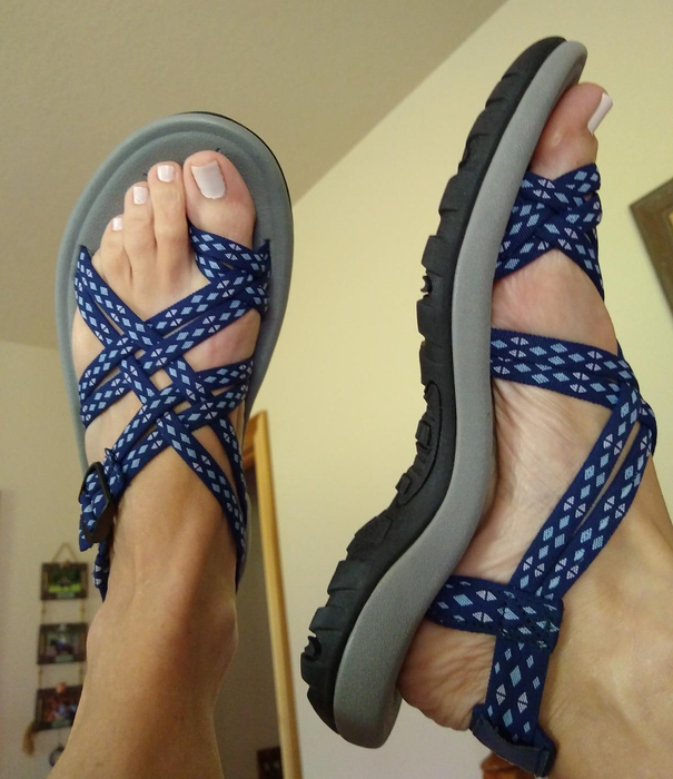 Person showcasing blue patterned strappy sandals, highlighting the design for a shopping article