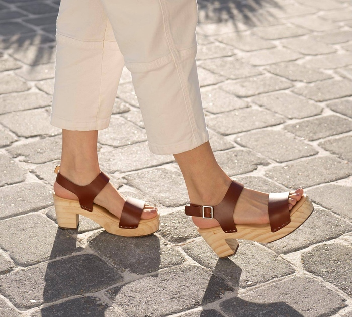 A model wearing brown open-toe sandals with thick wooden soles
