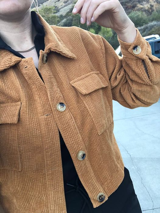Person sporting a corduroy button-up jacket with chest pockets, adding a classic touch to their look.