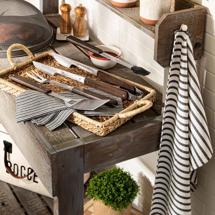 The grilling set featuring four tools made of wood and metal, placed next to a grill.