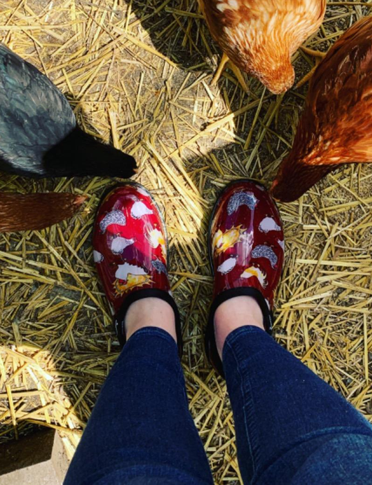 reviewer sporting red garden shoes adorned with chickens