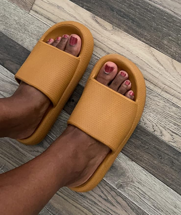 A reviewer wearing brown slide sandals.