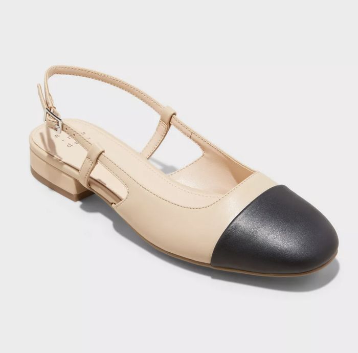 A beige T-strap flat with a striking black toe cap, a simple yet elegant combination