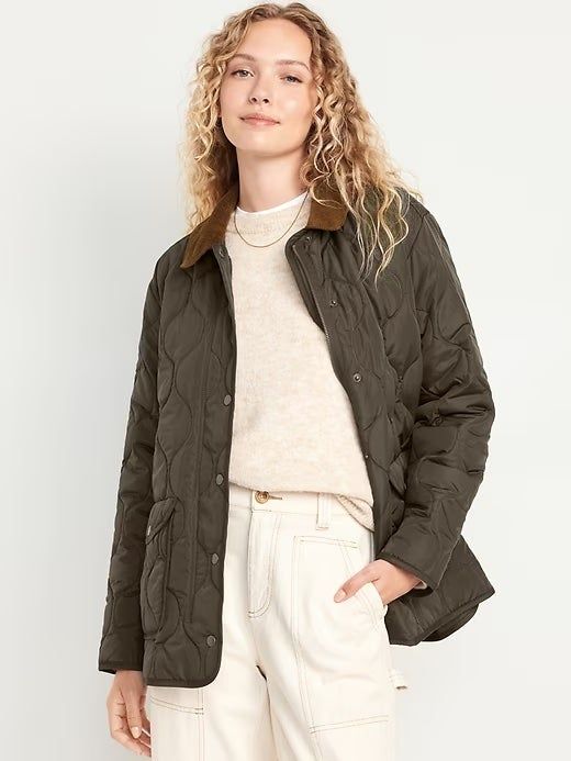 A woman wearing a cozy quilted jacket over a light shirt and high-waisted pants, showcasing winter fashion. Her wavy hair and relaxed expression complete the look.