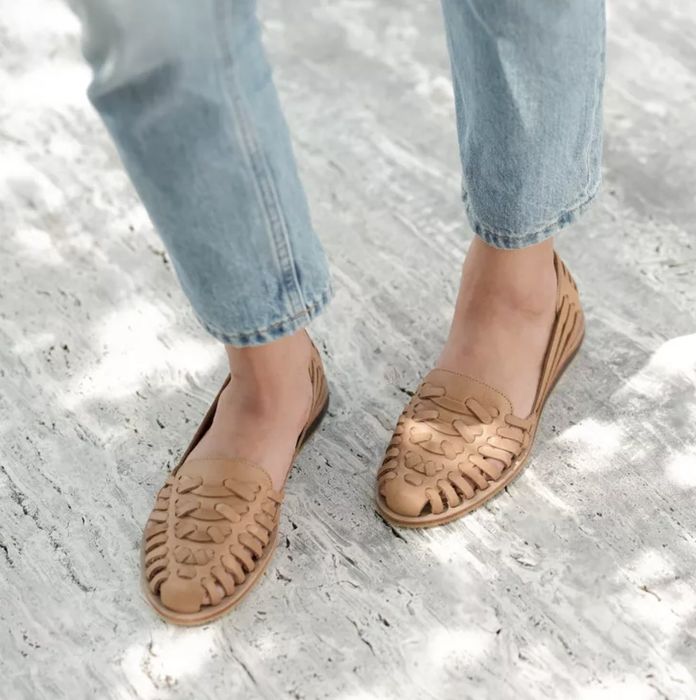 A close-up shot of a person wearing woven leather flats paired with cuffed jeans, showcasing a relaxed and comfortable style.