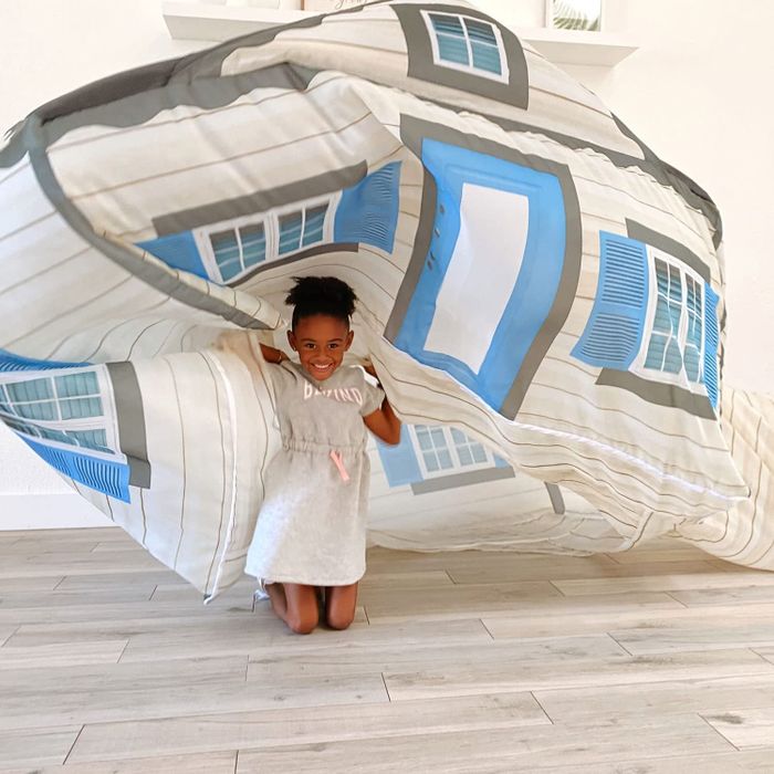 A child playfully flipping over an inflatable house fort from the inside.