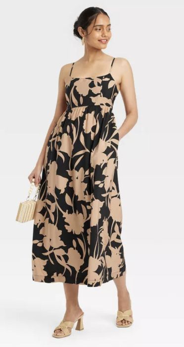 Model in a floral print midi dress, elegantly holding a clutch and posing gracefully