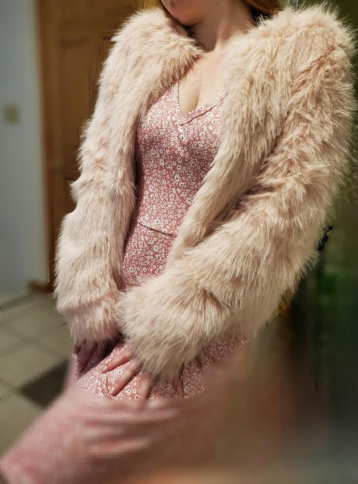 A person showcases a chic outfit featuring a pink floral dress paired with a fluffy faux fur jacket.