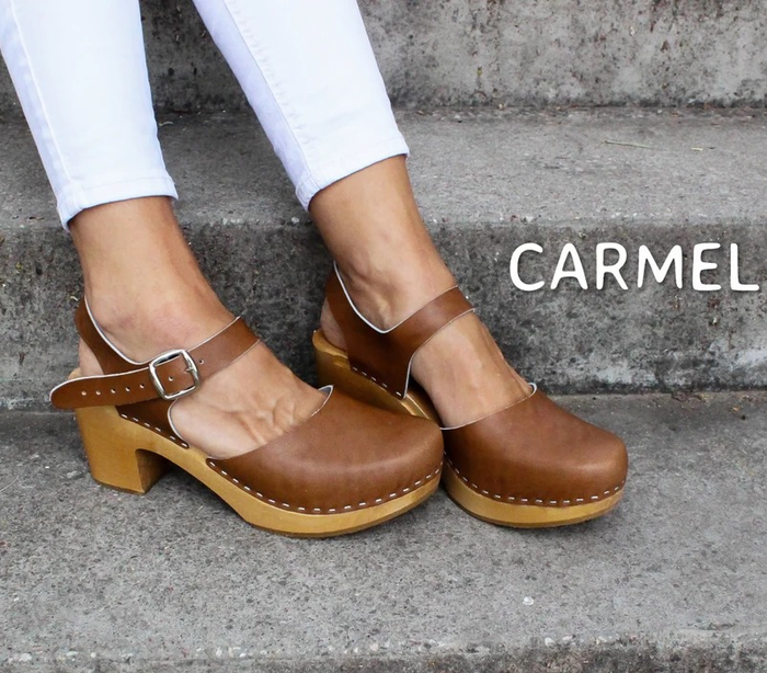 A model's feet showcasing brown wooden clogs.
