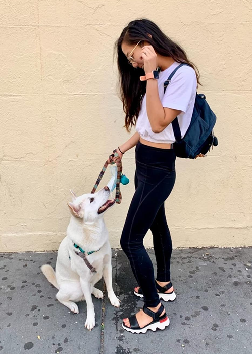 A reviewer photo of a person standing with their dog while wearing black and white sandals.