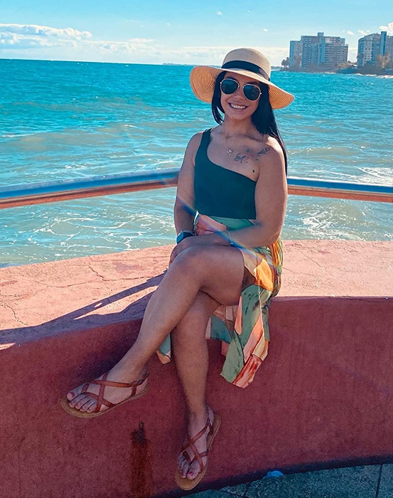 Reviewer sitting near the water, sporting tan sandals