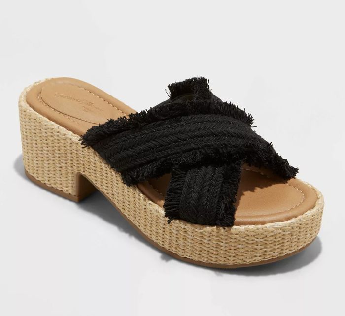 A black sandal with criss-cross straps, complemented by a beige platform sole for a stylish and modern look
