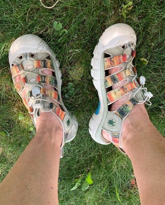 A reviewer's multicolored strappy Keen sandals displayed on grass.