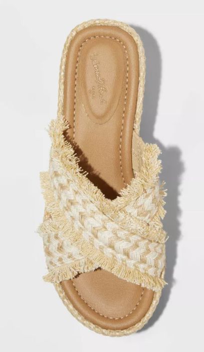 A cream-colored woven sandal with criss-cross straps, perfect for a light, breezy look in the warmer weather
