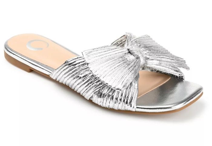 A silver slip-on sandal adorned with a pleated bow detail on the upper.