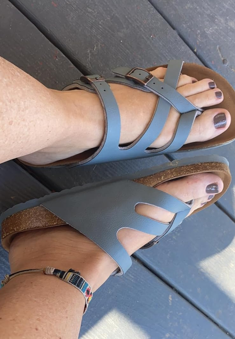 Person sporting blue strapped sandals and a multicolored ankle bracelet