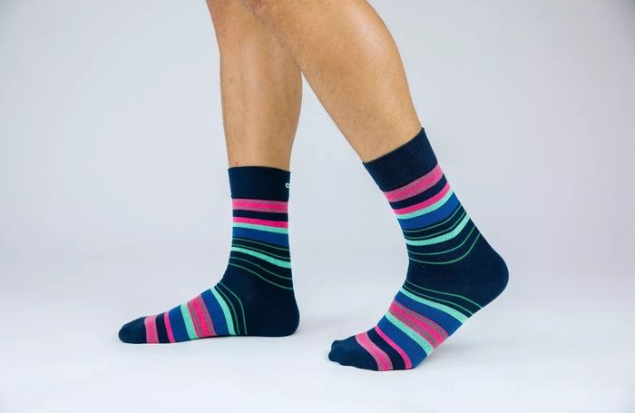 An adult model wearing a pair of socks adorned with colorful stripes, adding a touch of fun to their outfit.