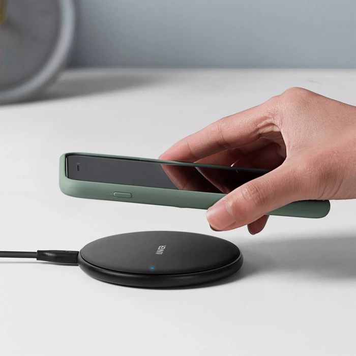 A model placing an iPhone on the round charging pad to power up.