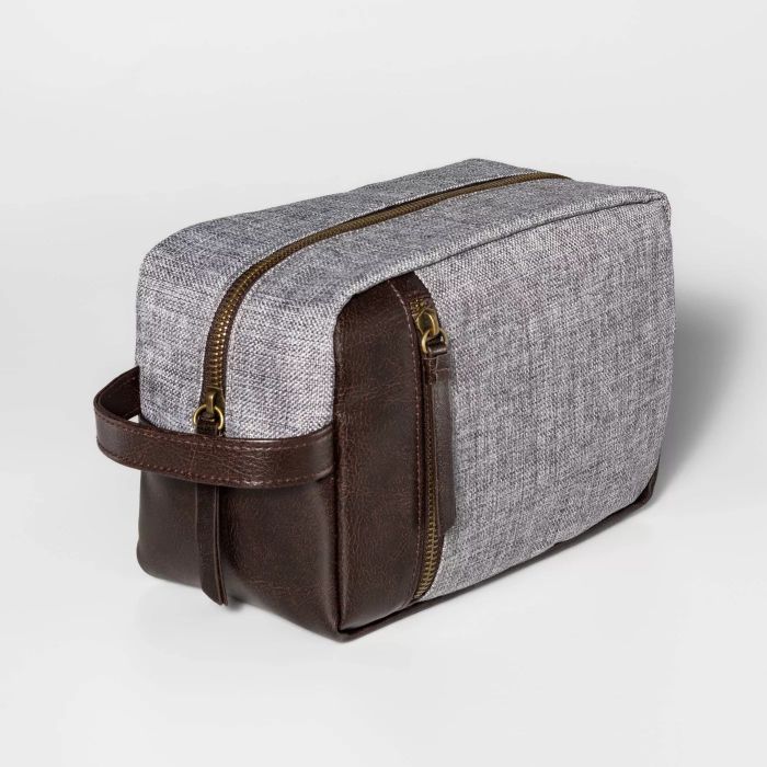 A dopp kit showcasing a sleek gray fabric exterior with contrasting brown leather accents.