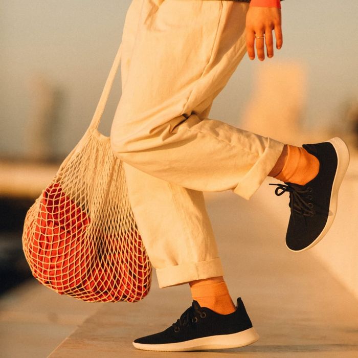 A person wearing black Allbirds with white soles.
