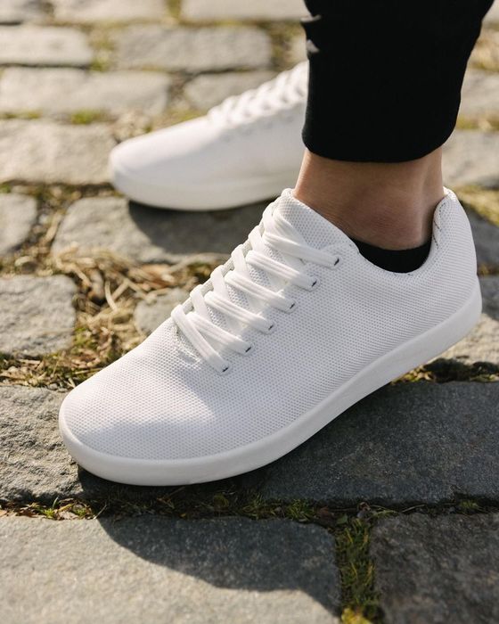 All-white sneakers on a model paired with black socks.