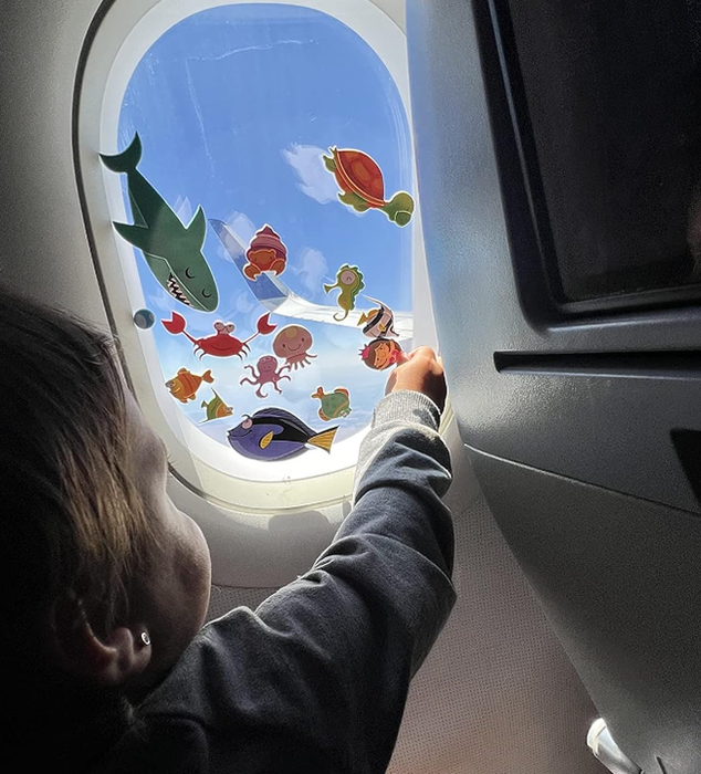 A child plays with sea creature stickers on an airplane window