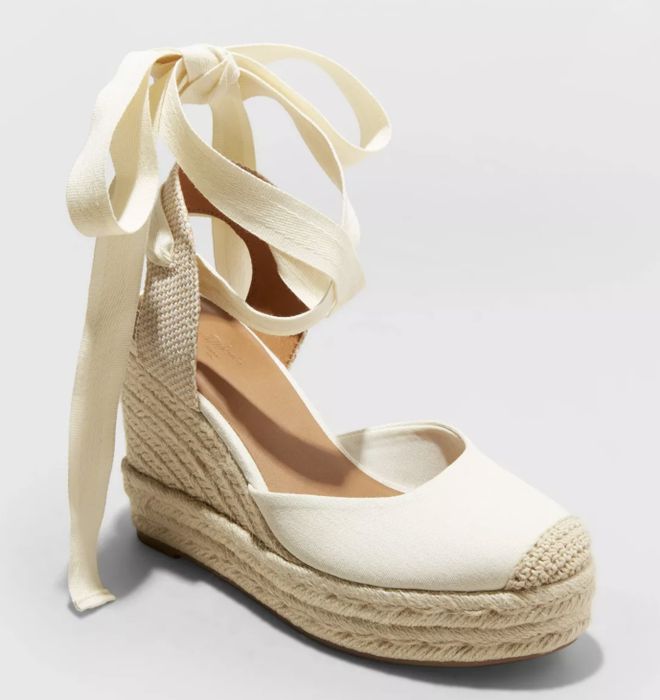 A single wedge espadrille featuring a woven heel and ankle wrap tie detailing, offering a laid-back yet elegant vibe.